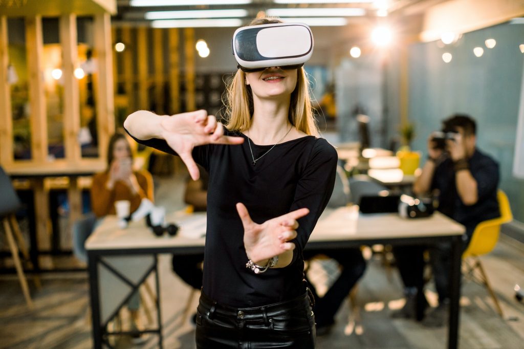 Woman in VR headset touching objects in virtual reality.